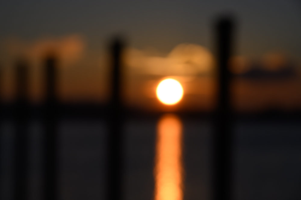 vollkommen unscharfer Sonnenuntergang zwischen Hafenpfosten