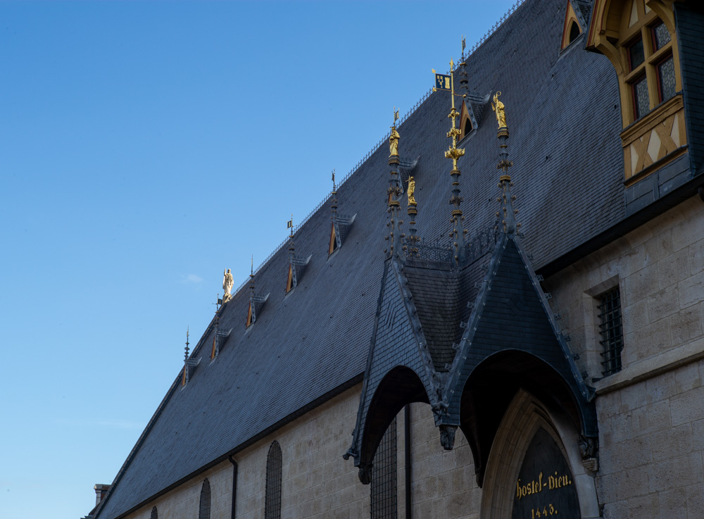 Dach des Hostel Dieu mit goldenen Figuren im Licht der untergehenden Sonne