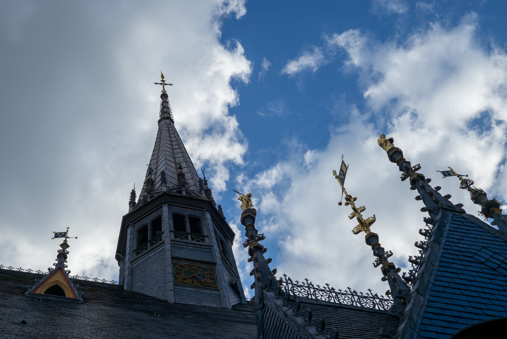 Dach des Hostel Dieu mit Wolken am Himmel und mit goldenen Figuren im Licht der untergehenden Sonne