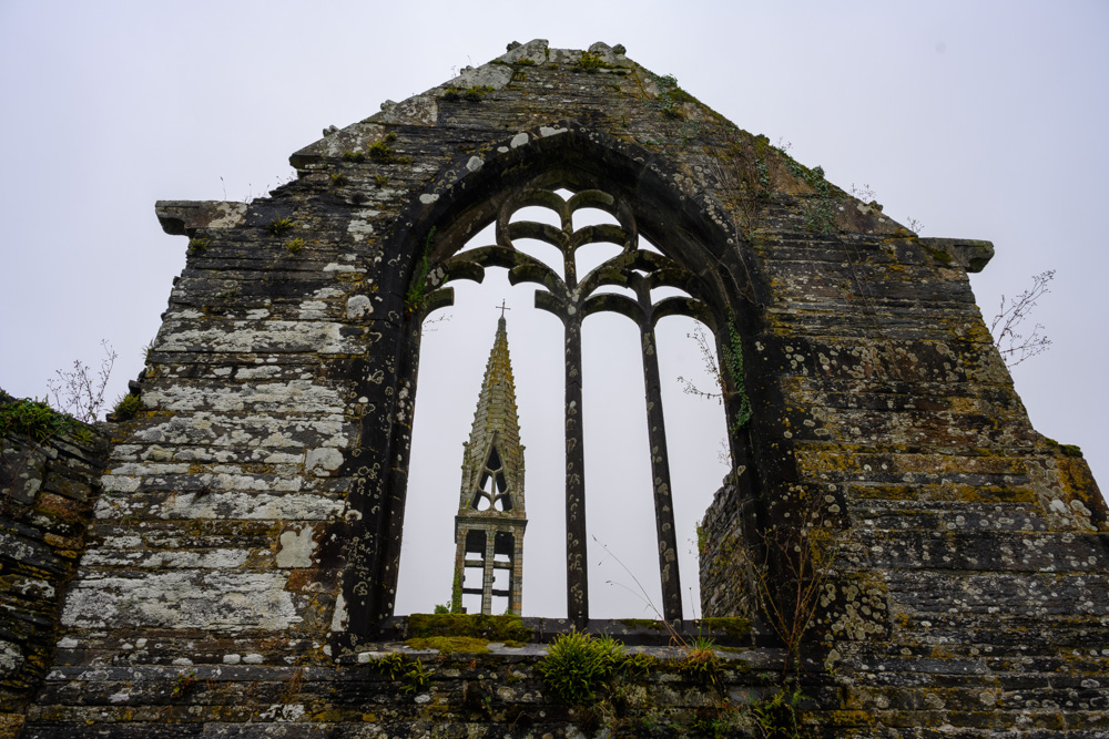 die Turmspitze des Kirchturmes durch die Reste eines alten Kirchenfensters