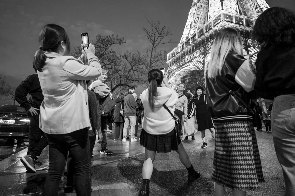 junge asiatische Frauen, die mit Mobiltelefonen den Eiffelturm photographieren