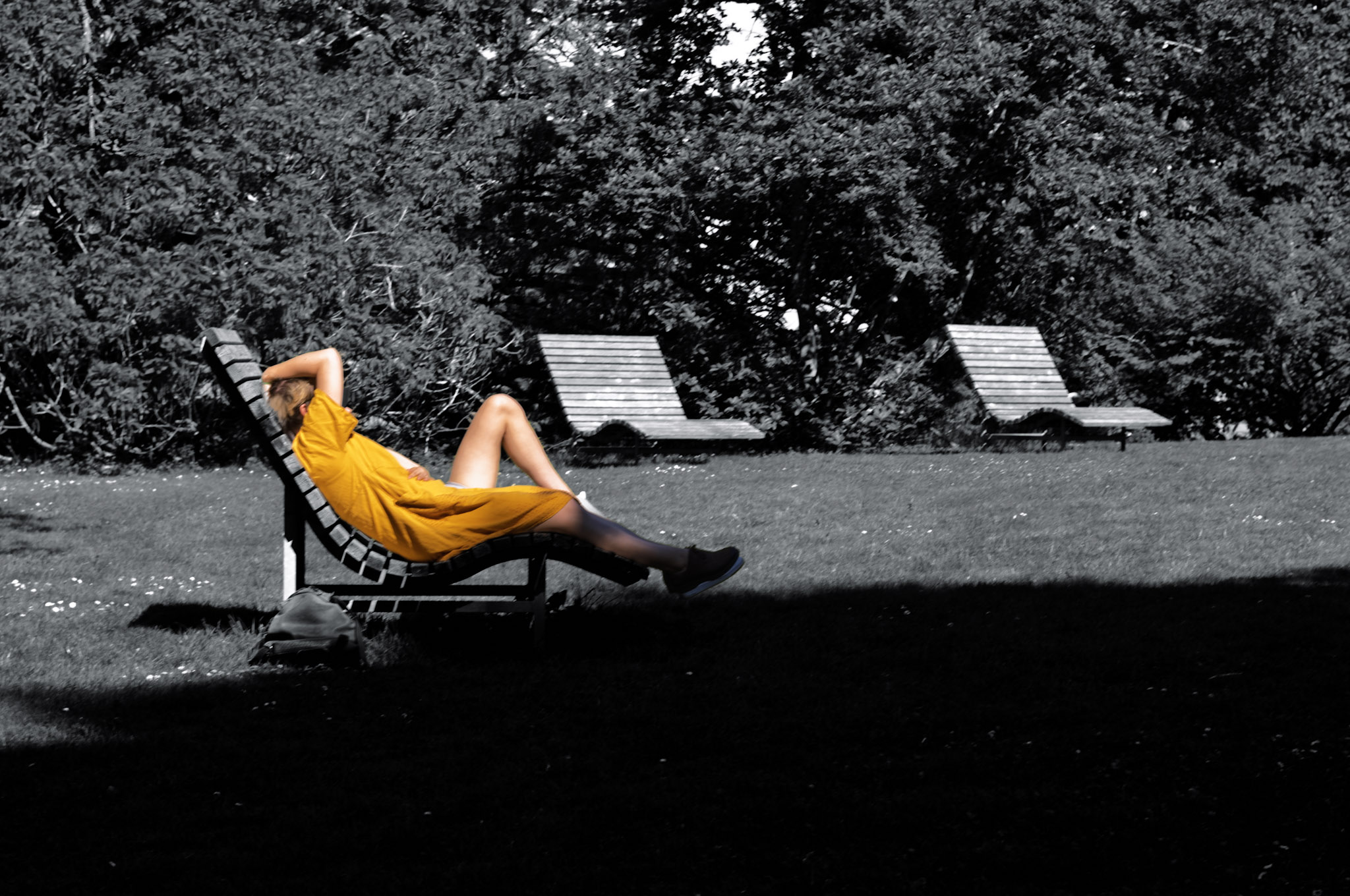 eine Frau in einem gelben Kleid auf einer Sonnenliege, im Hintergrund weitere leere Sonnenliegen
